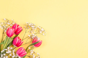 Bouquet of tulips and gypsophila on a yellow background. Place for text. Flat lay, top view.