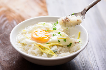 Thai rice soup or soft-boiled rice with pork and egg in the bowl with spoon for eating