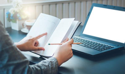 Closeup young asian woman working with laptop and writing on note