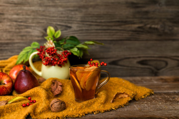 Fall harvest cornucopia. Cup of hot apple tea for fresh start of the day. Autumn season warm drink. Copy space on wood background.