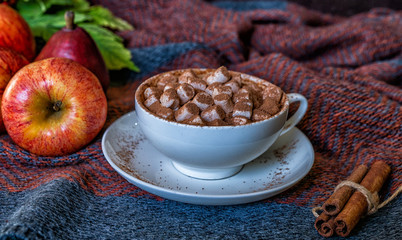 Autumn background. A mug of coffee on the dark background with yellow falling leaves, red berries and cones. Hello autumn. Instagram fashion drink composition.