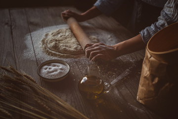 Obraz na płótnie Canvas Blurred female hands making dough for pizza. Baker kneading dough. An experienced chef prepares the dough with flour to make the pizza. Concept of cooking, Italy, food and diet. Toned image.