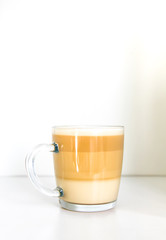 Hot coffee latte transparent glass cup on white background. Vertical shot.