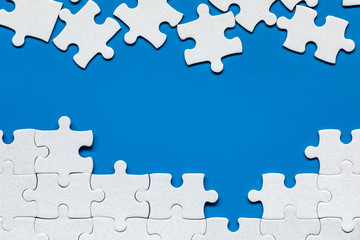White jigsaw puzzle. White puzzle pieces on color background. Unfinished white jigsaw puzzle pieces on color background. - obrazy, fototapety, plakaty