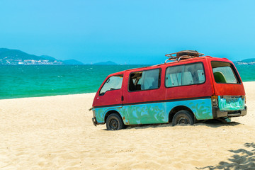 Old bus in sand of beach with blue sea background