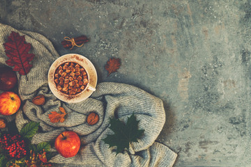 Autumn composition. Cup of coffee, warm scarf, autumn leaves on dark background. Toned image. Top view, copy space.