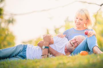 Fototapeta premium Elderly couple reading newspaper in garden at sunset. Concept couple elder love.