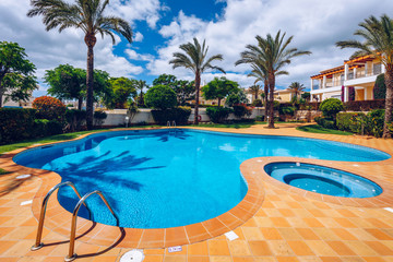 Swimming pool with stair. Grab bars ladder in the blue swimming pool. Poolside with blue clear water and ladder. Stair at the side of swimming pool, summer concept.