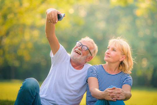 Elderly Couple Reading Newspaper In Garden At Sunset. Concept Couple Elder Love.