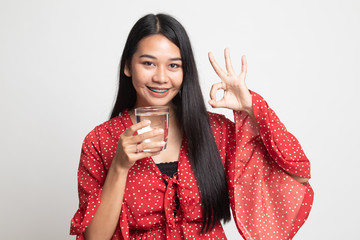 Young Asian woman show OK with a glass of drinking water.