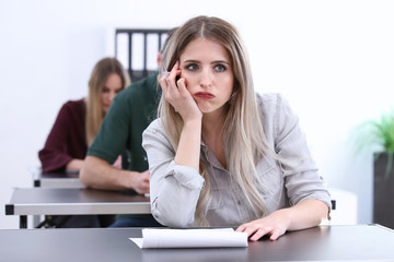Junge Frau sitzt in einer Prüfung und schaut unglücklich