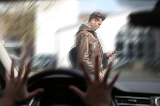 Mann l&auml;uft auf sein Handy schauend &uuml;ber die Strasse, und wird von einem Auto angefahren