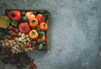 Composition with assorted raw organic fruits. Detox diet. Apples, pomegranate, grapes with autumn yellow leaves on a vintage tray. Flat lay with copy space.
