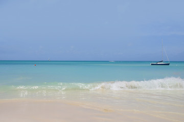 Fototapeta na wymiar Sand Beach of Antigua, dream beach with a little sailboat on the horizon, Caribbean Sea