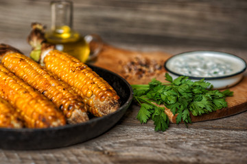Corn grilled with cheese and spices on the dark rustic background. Autumn food background. Fast food in the summer or fall. Toned image. Flat lay with copy space.