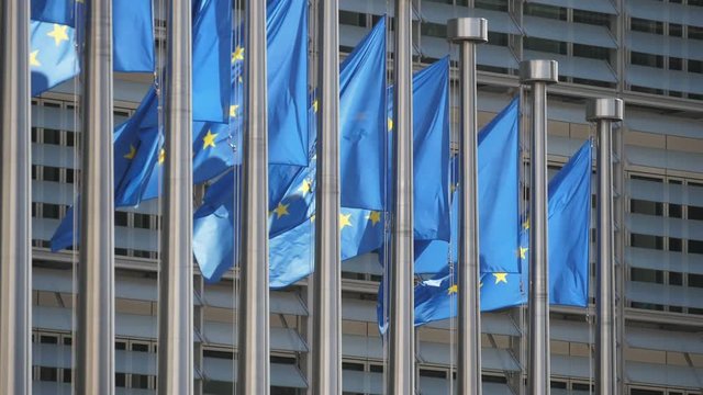 Beautiful EU flags waving at European Commission on a sunny day in slo-mo   