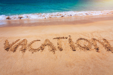 Vacation text on a beach. Vacation written in a sandy tropical beach. 