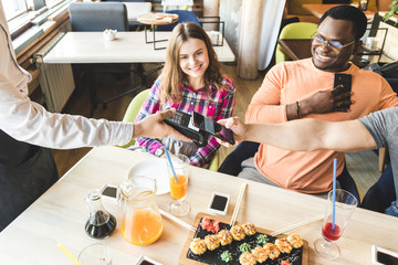 Young attractive woman paying in cafe with contactless smartphone payment