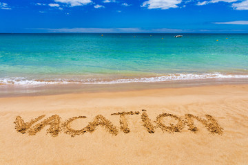 Fototapeta na wymiar Vacation text on a beach. Vacation written in a sandy tropical beach. 