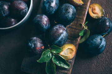 Colander with ripe juicy plums on table.