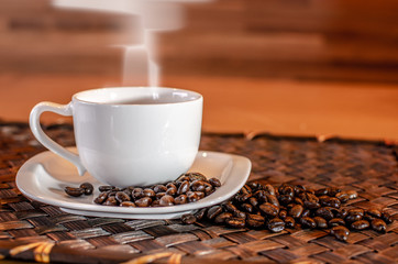 Cup of hot Coffee with smoke and coffee bean on wooden table