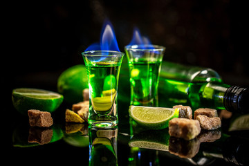 absinthe poured into a glass. alcoholic drink with brown sugar and lime. Absinthe or mint liquor shot