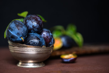 Bowl with ripe juicy plums on table. Fresh organic plums. Summer harvest. Autumn harvest. Beautiful still life. Toned image. Selective focus.