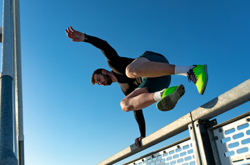 Men doing morning workout outdoors, sportsmen jumping over the fence.