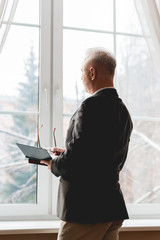 teacher in formal wear holding glasses and book and looking at window