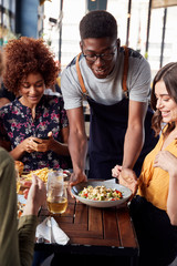 Waiter Serving Group Of Female Friends Meeting For Drinks And Food In Restaurant