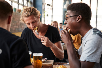Three Young Male Friends Meeting For Drinks In Restaurant