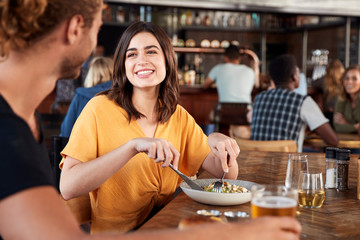 Couple On Date Meeting For Drinks And Food In Restaurant