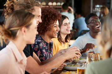 Group Of Young Friends Meeting For Drinks And Food In Restaurant
