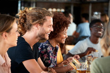 Group Of Young Friends Meeting For Drinks And Food In Restaurant