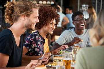 Group Of Young Friends Meeting For Drinks And Food In Restaurant