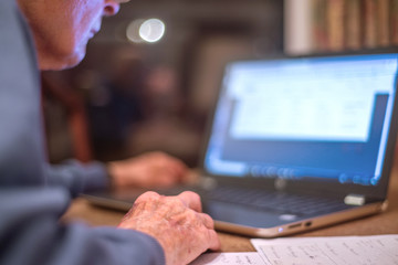 Elderly man on a laptop computer checks his online banking,Hampshire,England,U.K.
