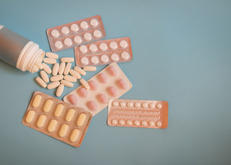 Bottle with pills and blisters with pills and capsules on blue background.