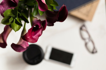 Place of work, flower red color and smart phone black screen and  book  and coffee cup on  white background 
