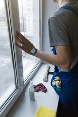Close-up of a man in uniform and blue gloves washes a windows with window scraper. Professional home cleaning service