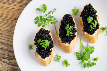 tapas with halibut caviar and butter decorated with garden cress in white plate on wooden top