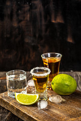Alcoholic drink concept. Mexican tequila with lime and salt on rustic wood background. space for...