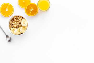 granola with banana slices and orange juice for breakfast on blue background top view copyspace