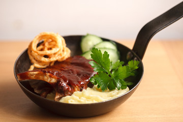 baked barbecue ribs with mashed potatoes in a cast iron pan