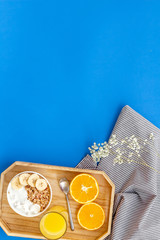 Healthy granola with banana and orange juice for colorful breakfast on blue background top view mock-up