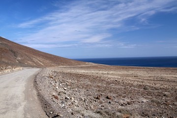 Dirt road along north-west coast through bare arid landscape of Fuerteventura, Canary Islands