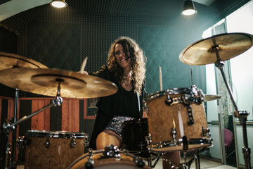 Woman playing drums during music band rehearsal