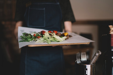 Waiter serving salad and grilled meat at restaurant, close up view. Eating and leisure concept. Toned image. Selective focus.