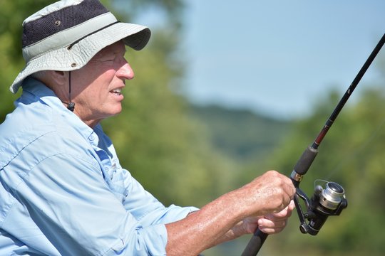 Old Senior Male Fisherman Resting With Rod And Reel Fishing