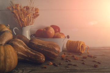 Autumn fruit and vegetables background. Fall Thanksgiving seasonal. Nature background. Wooden old table in an autumnal warm day in the sunshine and flowers in rustic vase. Soft focus. Toned image.