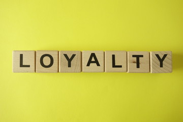 Word loyalty from wooden letters on yellow background